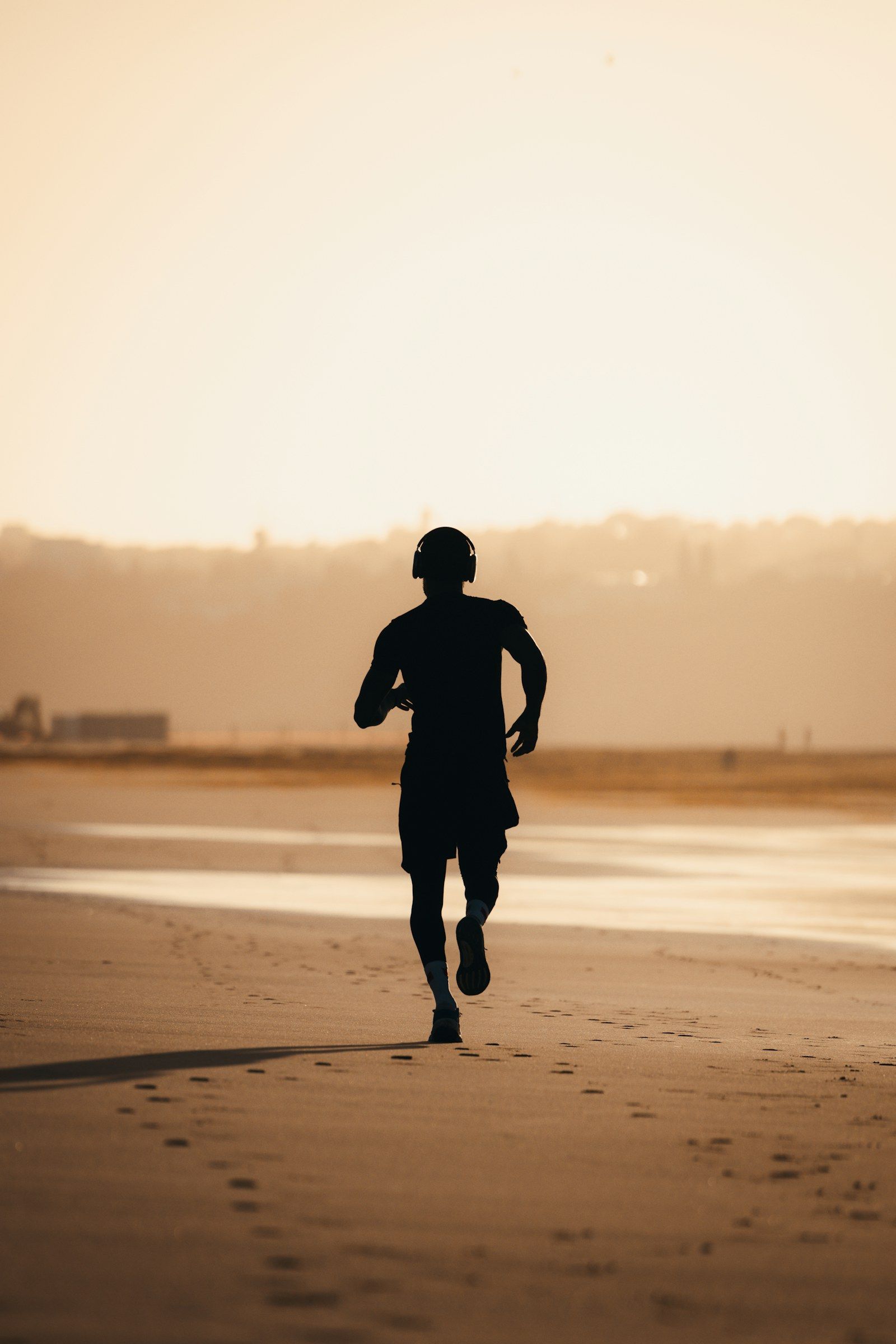 Silhouette d’un coureur sur le sable, face au soleil couchant