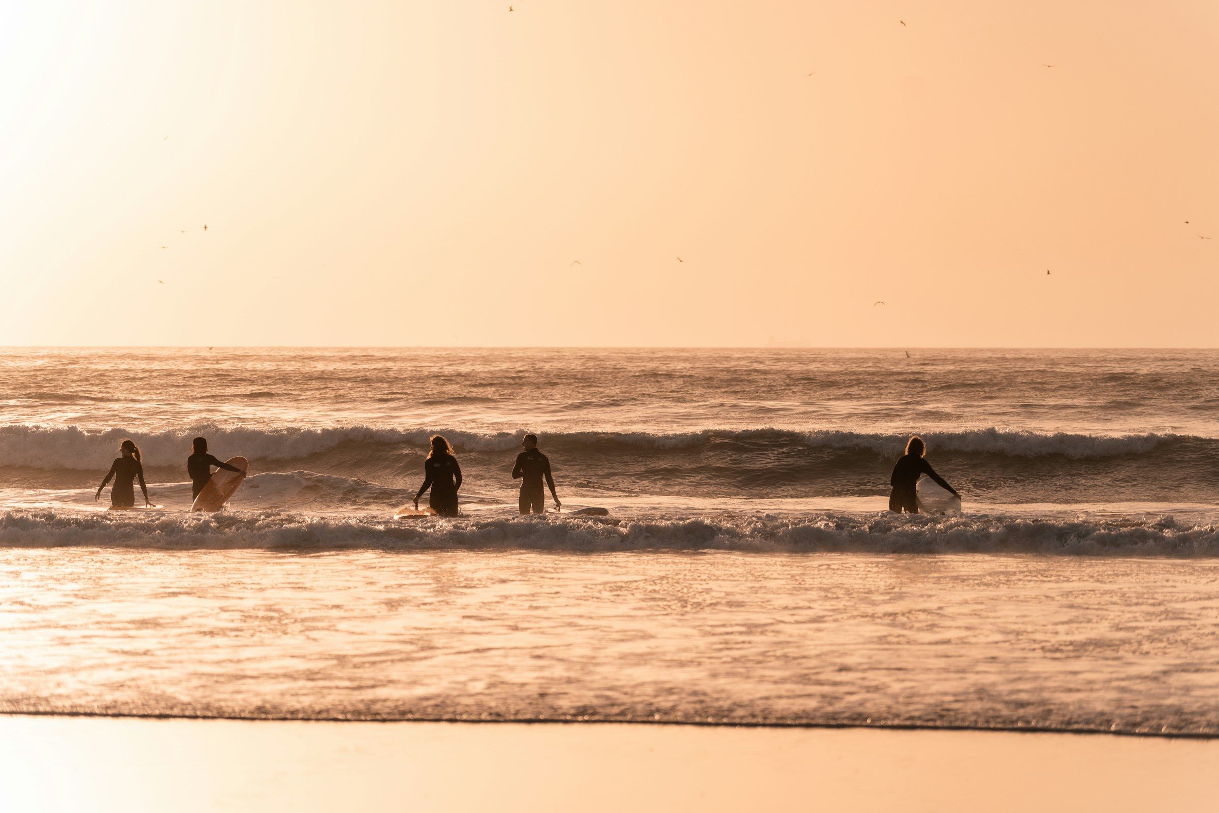 Des surfeurs dans les vagues au coucher du soleil